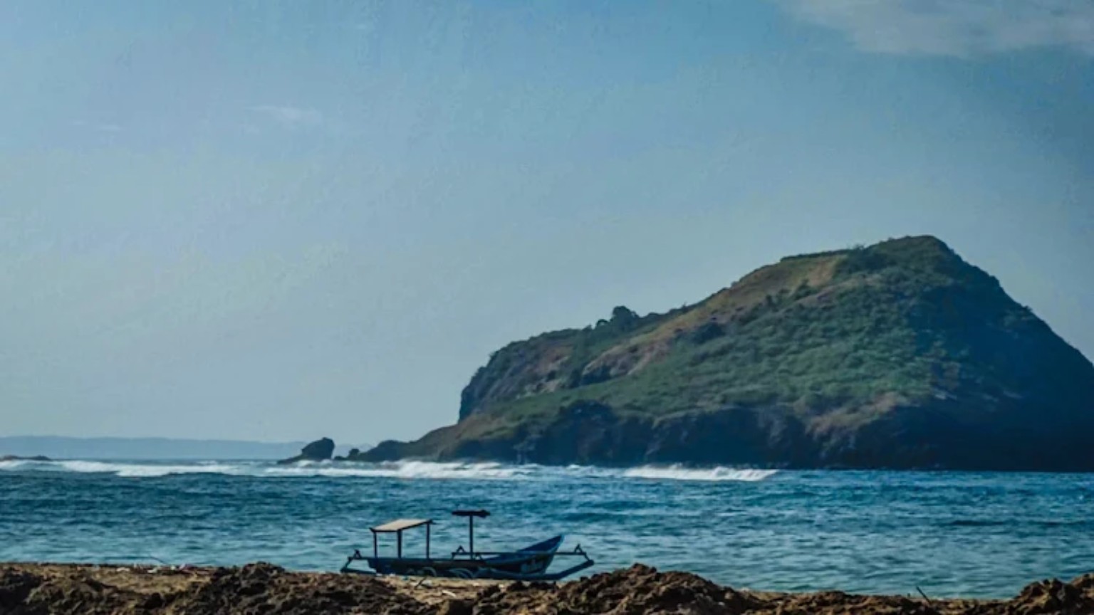 A local outrigger boat beneath the Are Guling headland